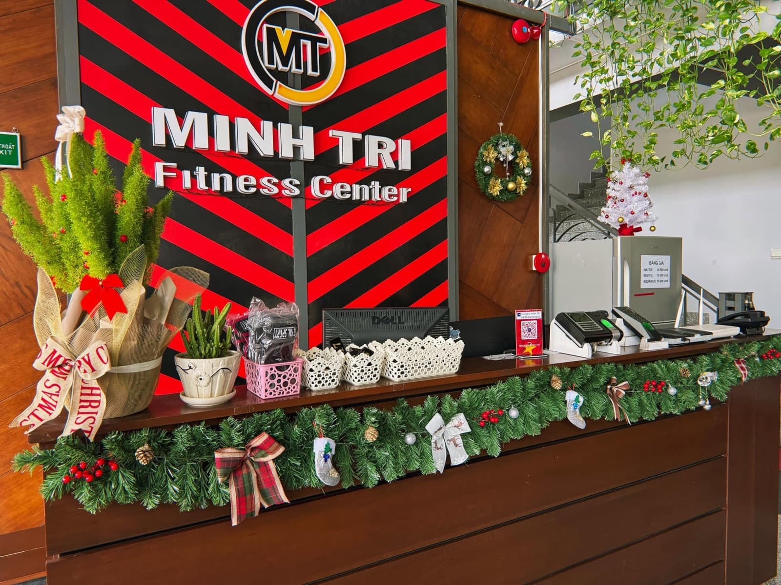 Quầy lễ tân dưới bảng hiệu sọc đỏ đen Minh Trí Fitness Center